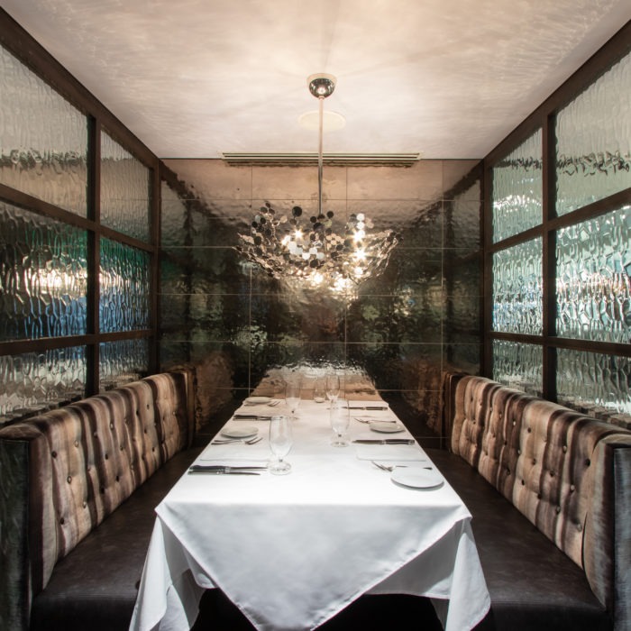 A restaurant booth with a set table surrounded by glass window panes.