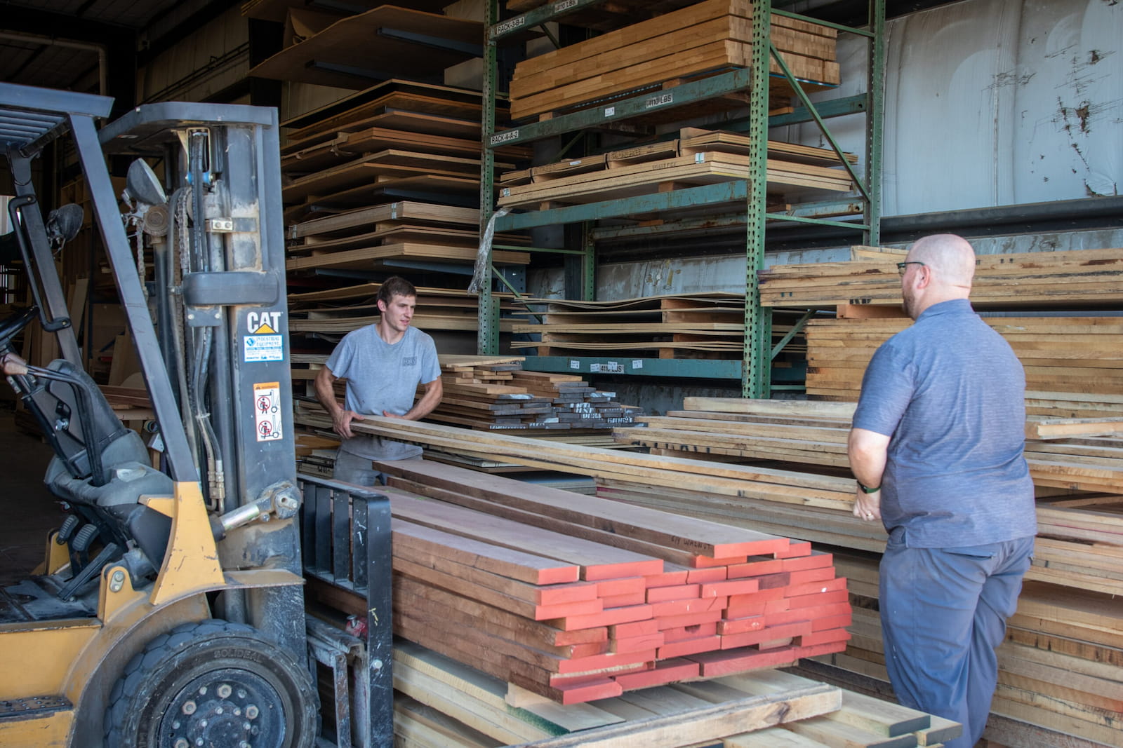 Seven Trees Woodworking employees carrying long palettes of wood